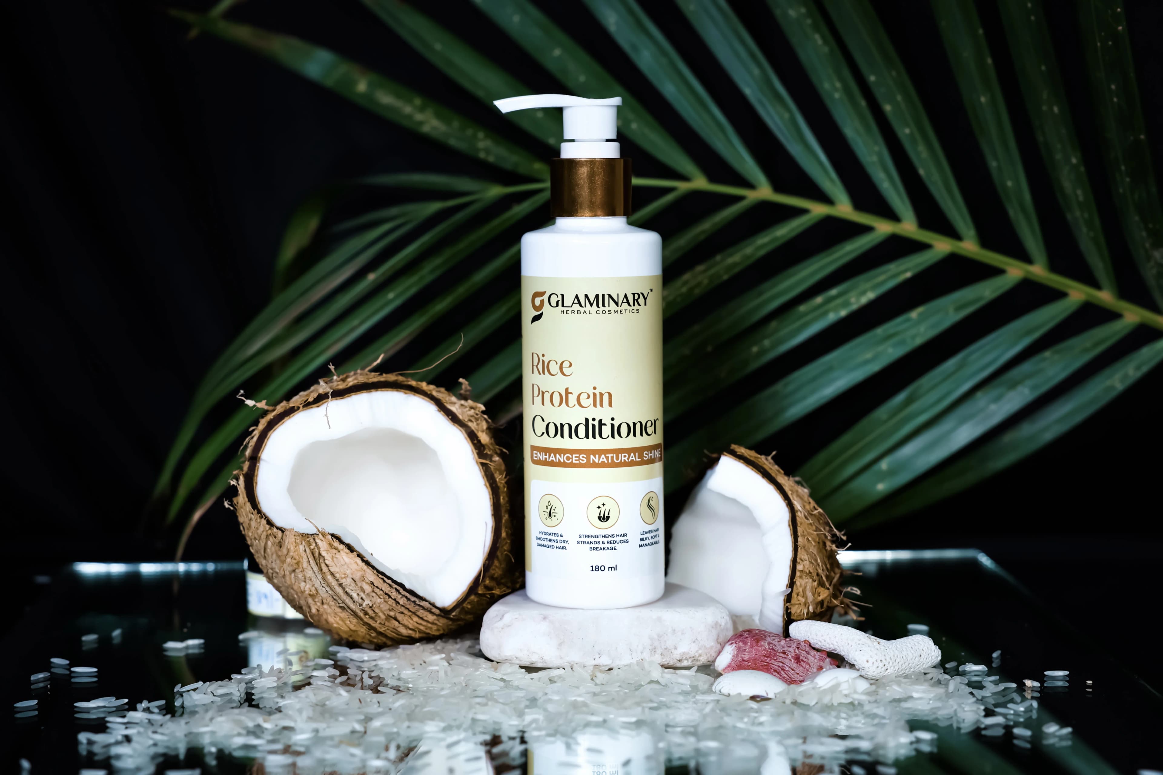Glaminary Rice Protein Conditioner on a white stone with split coconuts, rice and a palm leaf against black